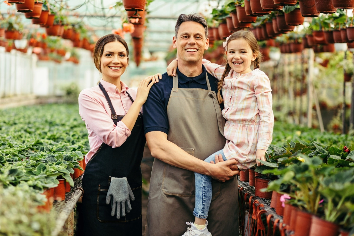 Husband, wife, and daughter standing together in a green house
